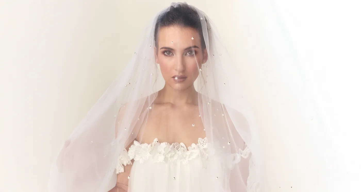 Model in a pearl-scattered veil from the Sarah Stoute Bespoke collection, gazing straight into the camera